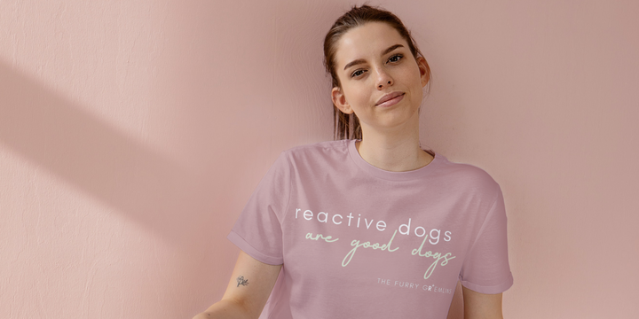 a dark haired girl wearing a reactive dogs are good dogs blush pink shirt with a peach background